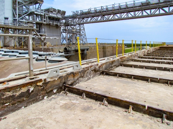 Large-format photograph: Pad Deck, Launch Complex 39-B, east side of Flame Trench, with Cutout area for Crawlerway Grid Panels exposed following their removal, along with the removal of the Foam Concrete and Sand upon which they  were placed. Visible along the bottom of the Cutout are the 1½” steel-plate Embeds which they were originally bolted down to. Photo credit: Withheld by request. Photo credit: Withheld by request.